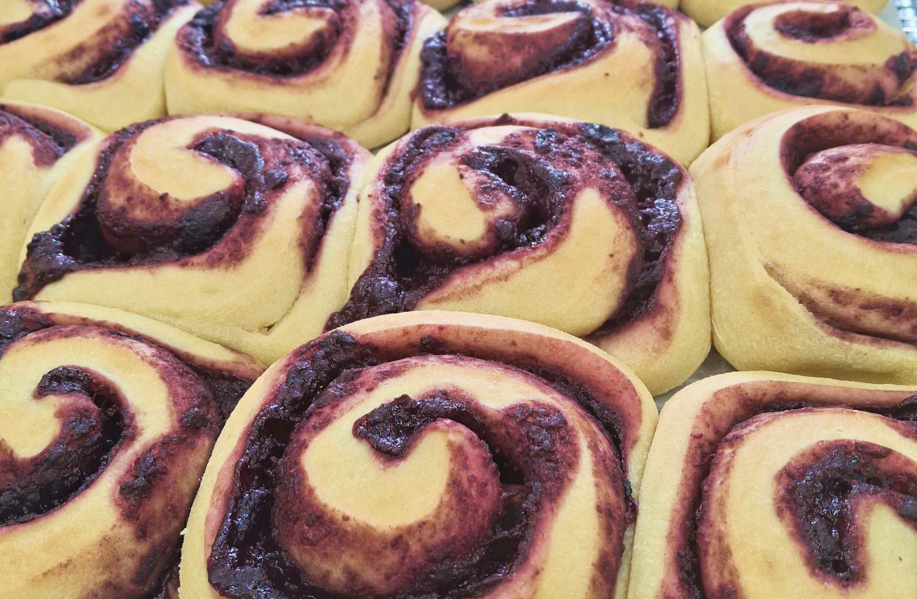 Fresh baked blueberry rolls with a golden glaze, cooling on a wire rack